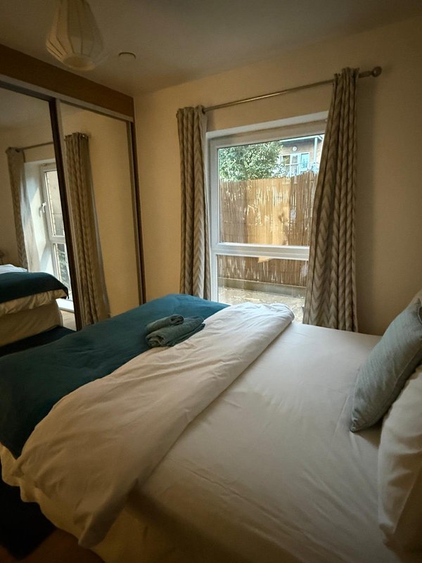 Bright bedroom with two single beds, cream and teal bedding, and patio doors overlooking garden