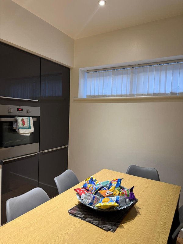 Modern kitchen with black cabinetry, dining table, chairs, and bowl of snacks