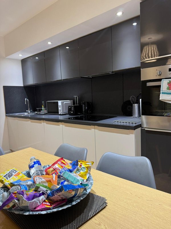 Modern kitchen with black and cream cabinetry, black countertop, and dining table with snacks