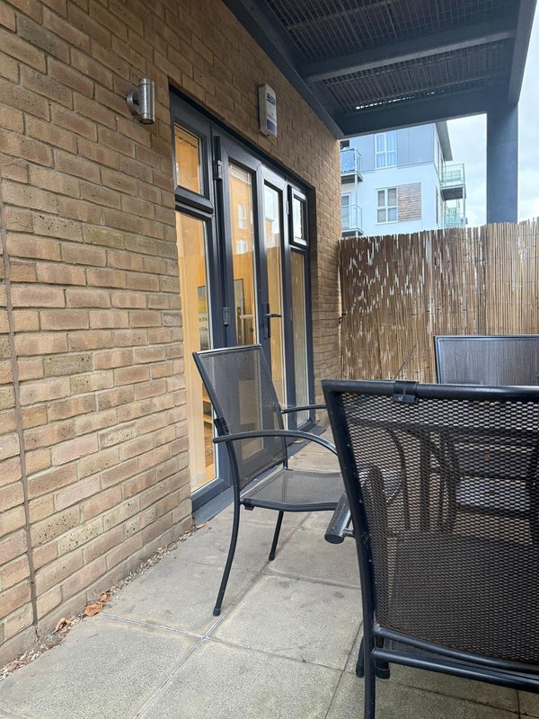 Brick exterior patio with black metal chairs and wooden fence screening