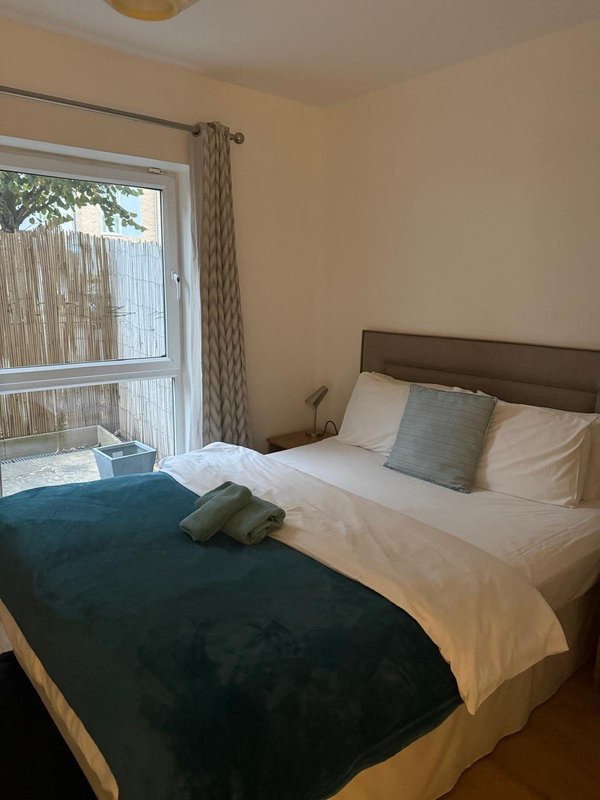 Bedroom with double bed, teal and white bedding, wooden headboard, and patio door access