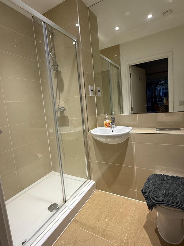 Modern bathroom with walk-in shower, vanity sink, mirror and tiled walls