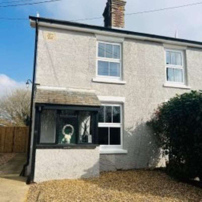 Semi-detached house with cream rendered facade, black trim, front garden and driveway