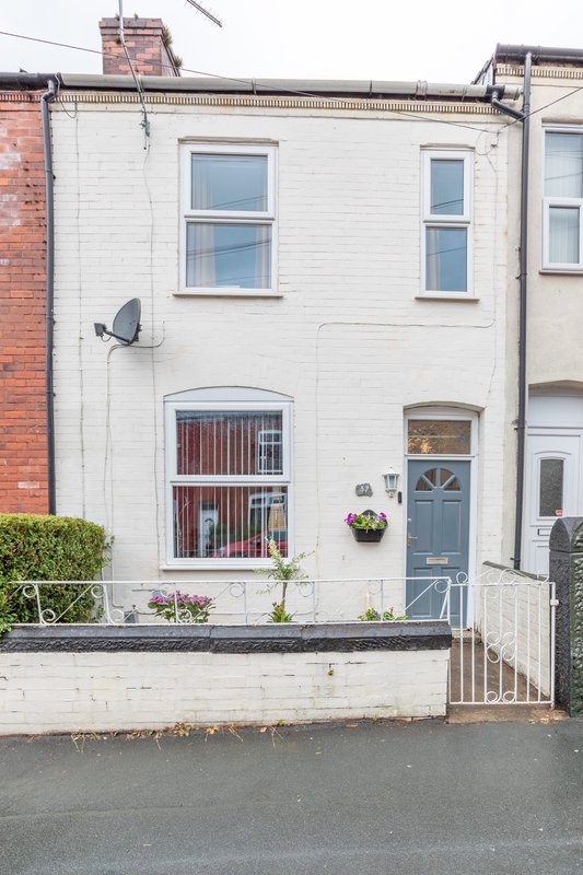 White-painted terraced house with blue door, front garden and street view