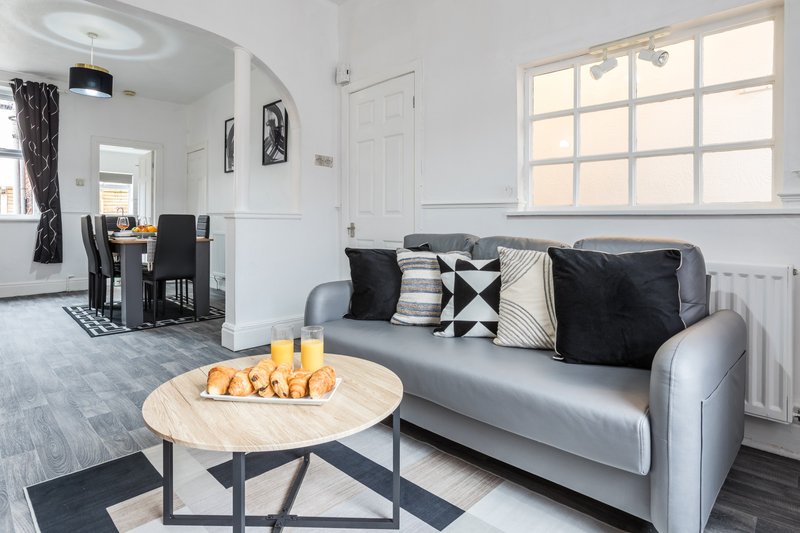 Modern living room with grey sofa, round wooden coffee table, and large windows