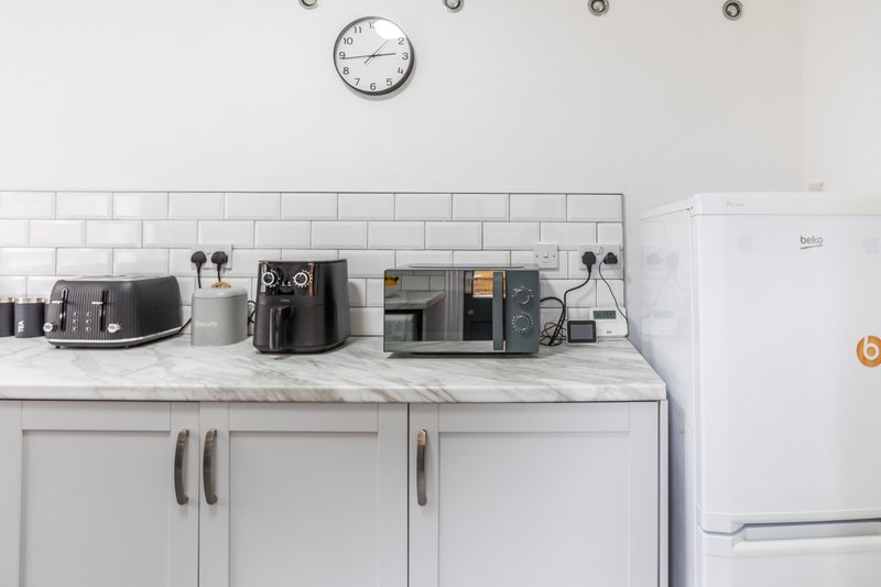 Modern kitchen counter with white subway tiles, stainless steel appliances, and wall clock
