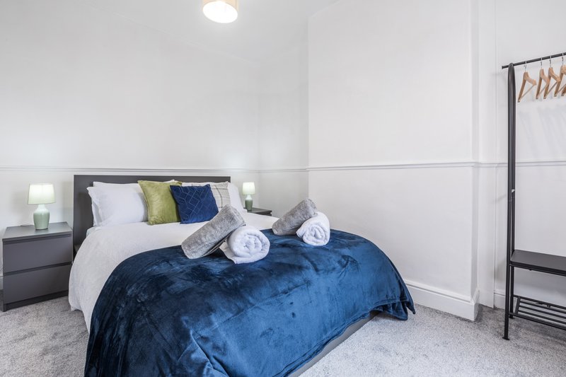 Modern bedroom with double bed, blue velvet duvet, decorative pillows and bedside lamps