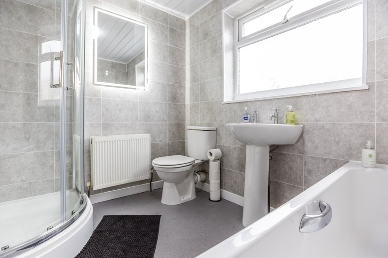 Modern bathroom with shower cubicle, toilet, pedestal sink, bathtub and radiator