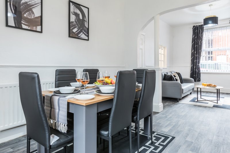Open-plan dining and living area with table, chairs, sofa and window views