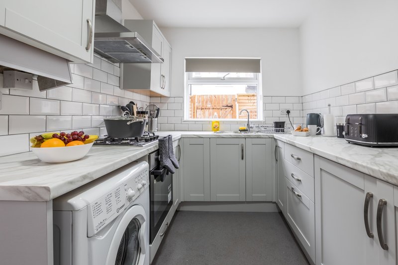 Modern kitchen with white subway tile, grey cabinetry, marble countertops and integrated appliances