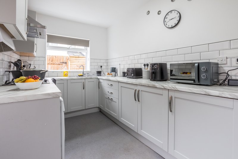 Modern kitchen with white cabinetry, stainless steel appliances, subway tile backsplash and window