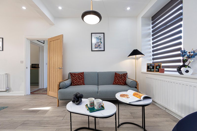Modern living room with grey sofa, coffee tables, pendant light and large window with blinds