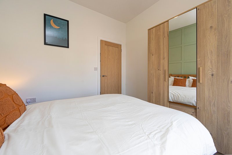 Bright bedroom with double bed, wooden wardrobe, mirror doors and wall art