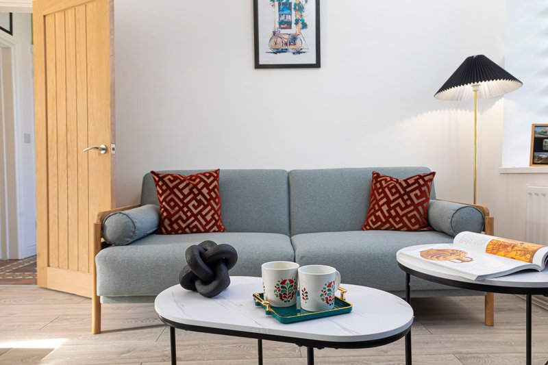Modern living room with grey sofa, patterned cushions, white coffee table and floor lamp