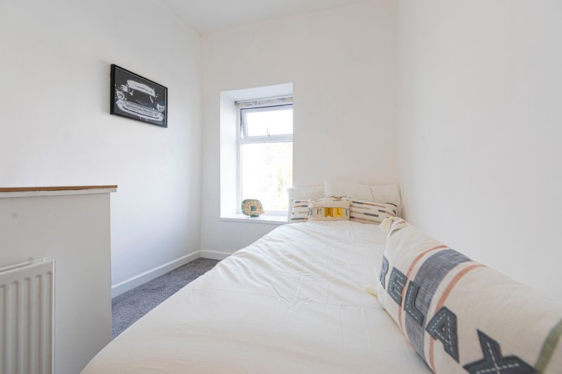 Bright bedroom with single bed, window, radiator and framed picture on wall