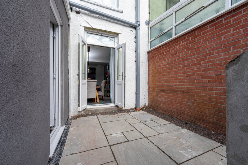 Exterior patio area with paving slabs, brick wall, and glass door entrance