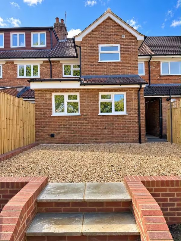 Brick townhouse exterior with driveway, wooden fence, and front steps