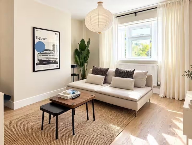 Bright living room with cream sofa, wooden coffee table, potted plant and framed artwork