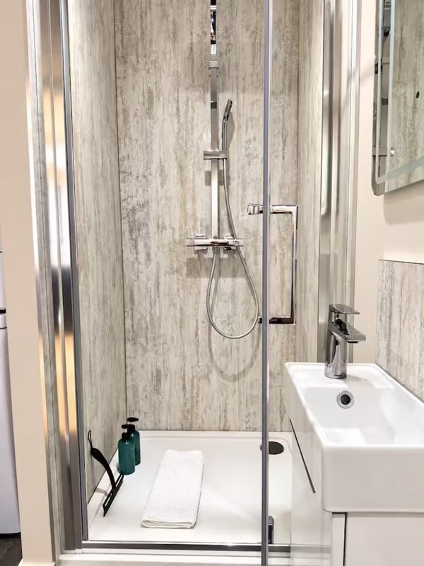 Modern bathroom with shower enclosure, white basin sink, and grey tile walls