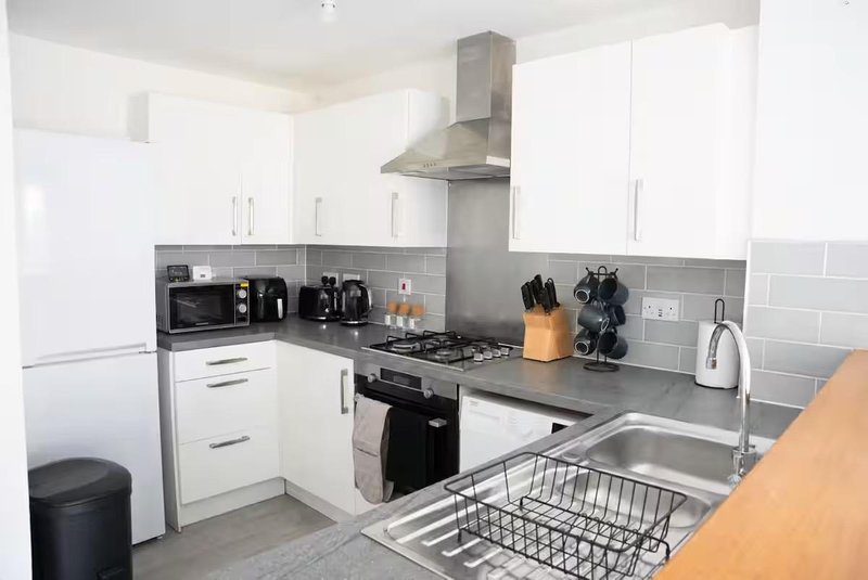 Modern kitchen with white cabinets, grey subway tile backsplash, black countertop and stainless steel appliances