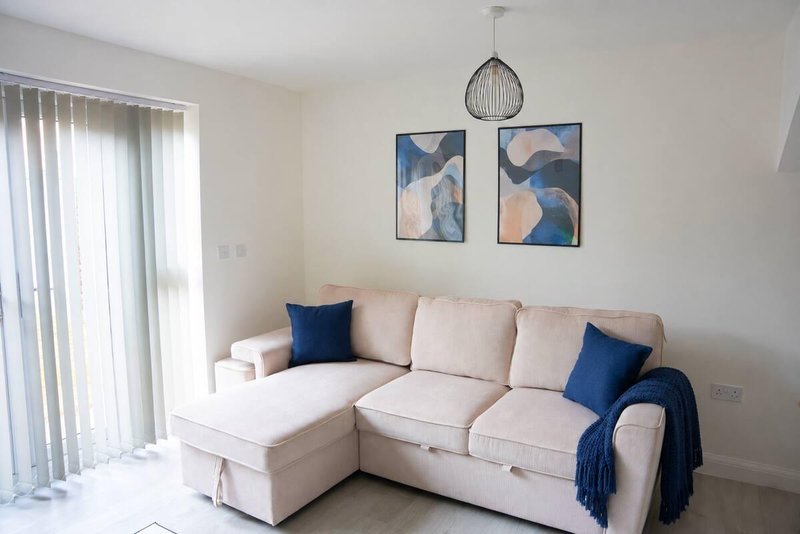 Bright living room with cream corner sofa, blue cushions, pendant lamp and abstract wall art