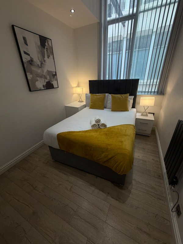 Modern bedroom with double bed, yellow bedding, black headboard and matching cushions