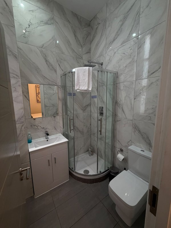 Modern bathroom with marble-effect tiles, corner shower enclosure, vanity sink and toilet