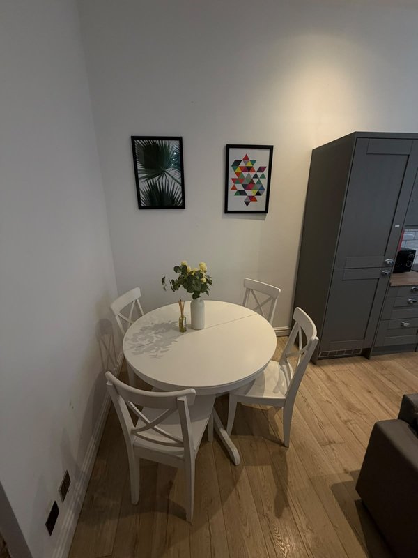 Dining area with round white table, four white chairs, and framed wall art