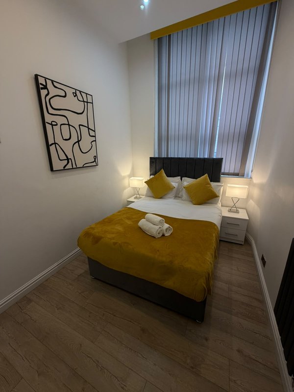 Modern bedroom with double bed, yellow bedding, wall art, and vertical blinds