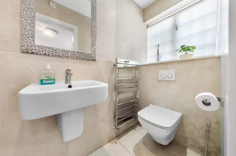 Modern bathroom with wall-mounted sink, toilet, heated towel rail and decorative mirror