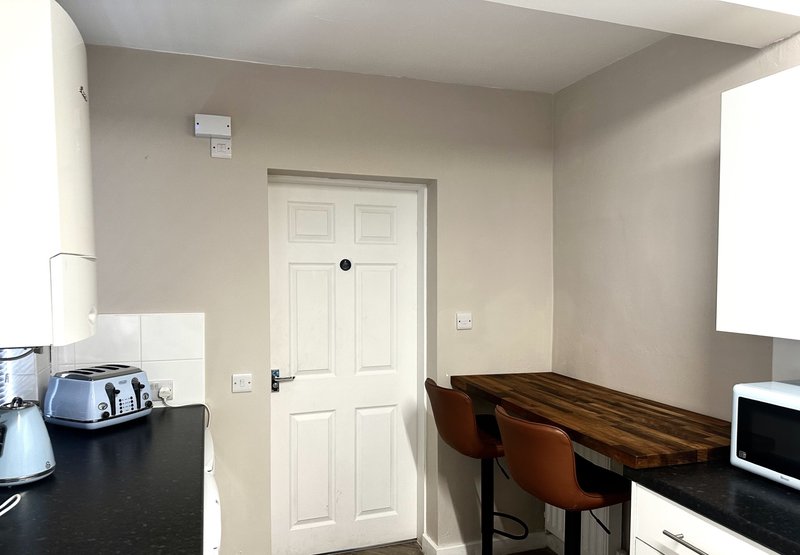 Modern home office with desk, chair, kettle, and white paneled door
