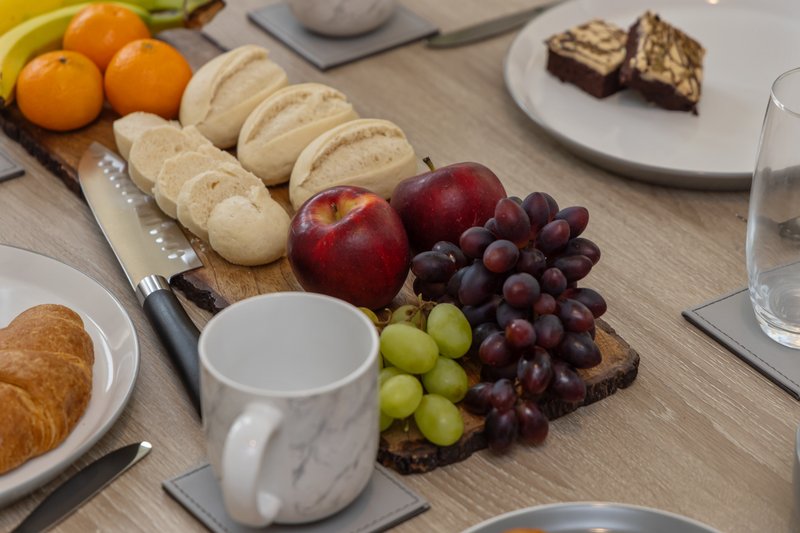 Dining table with fruit, bread, pastries, and mug for breakfast service