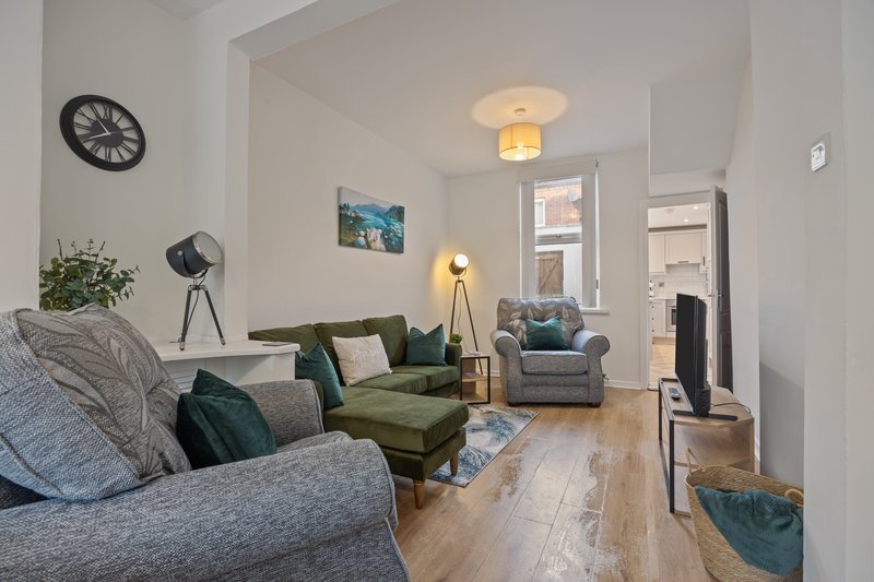 Open-plan living room with grey sofa, green armchair, wooden floor and pendant lighting