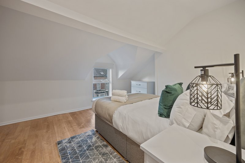 Bright attic bedroom with double bed, wooden flooring, and sloped ceiling with skylight