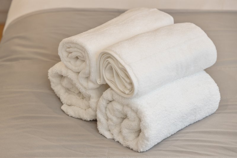 Rolled white towels arranged on a grey bed