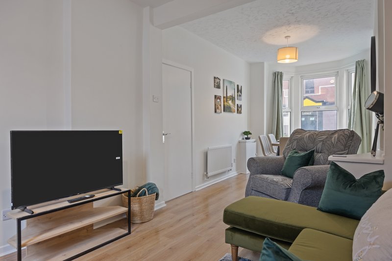 Bright living room with TV, wooden floor, upholstered seating and window view