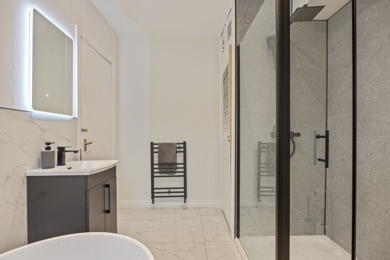 Modern bathroom with vanity sink, illuminated mirror, freestanding tub and walk-in shower