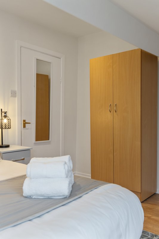 Modern bedroom with double bed, wooden wardrobe, and en-suite bathroom door