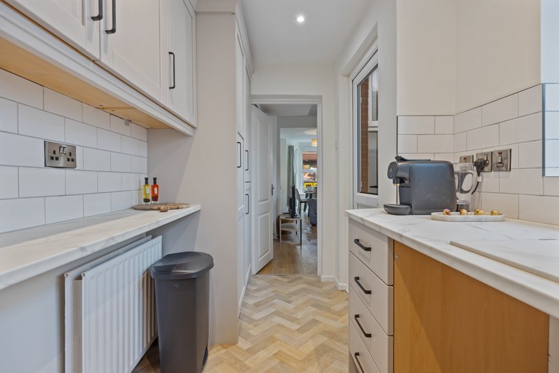 Modern kitchen with white cabinetry, wood base units, herringbone flooring and breakfast bar