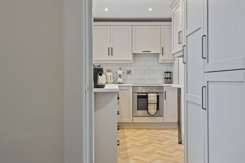 Modern kitchen with white cabinetry, stainless steel appliances, subway tile backsplash, and herringbone wood flooring