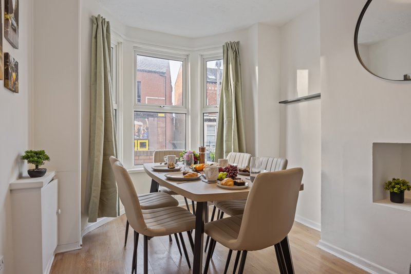 Bright dining area with table, four chairs, bay window and city views