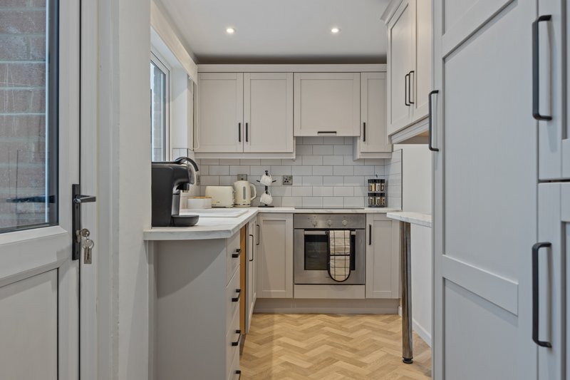 Modern kitchen with white cabinetry, subway tile backsplash, stainless steel appliances and herringbone flooring