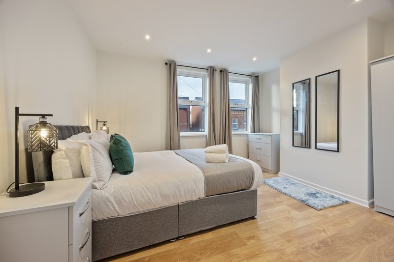 Modern bedroom with double bed, wooden floor, large windows and contemporary furnishings