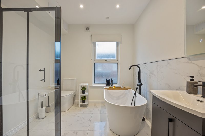 Modern bathroom with freestanding bathtub, walk-in shower, double vanity and window view