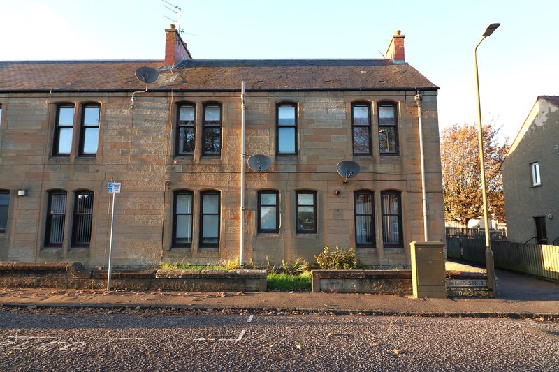 Stone terraced house with multiple windows, chimneys and front garden area