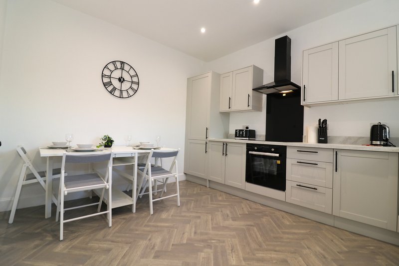 Modern kitchen with cream cabinetry, black appliances, dining table and chairs