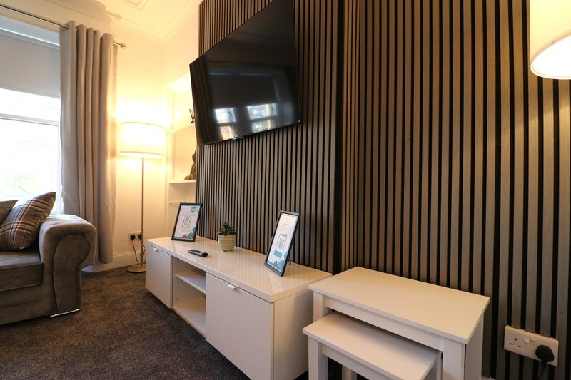 Modern living room with white media console, wall-mounted TV, and striped accent wall