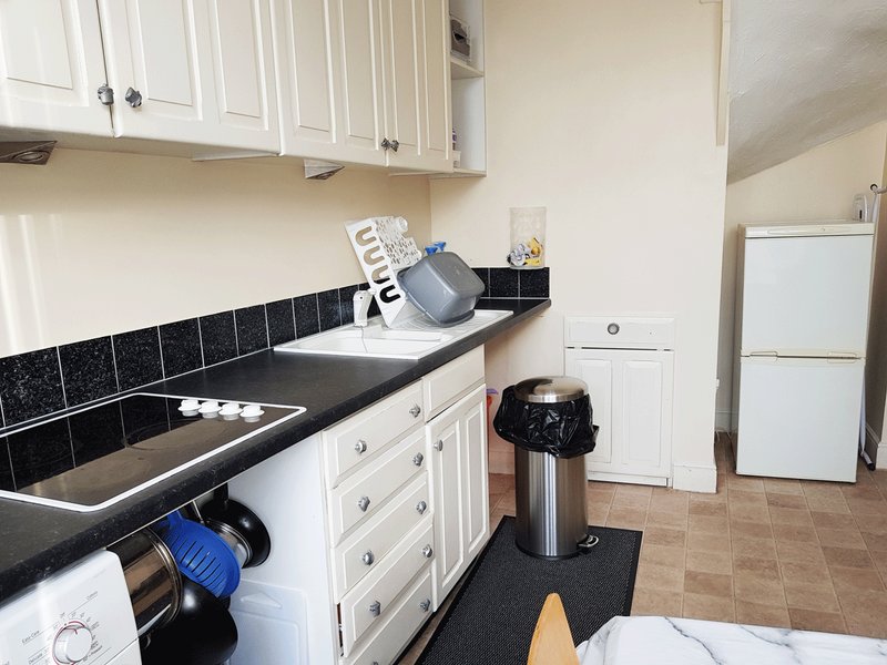 Kitchen with white cabinetry, black tiled backsplash, stainless steel appliances and countertop items