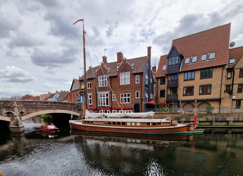 Riverside townhouses and historic buildings with moored boats and bridge