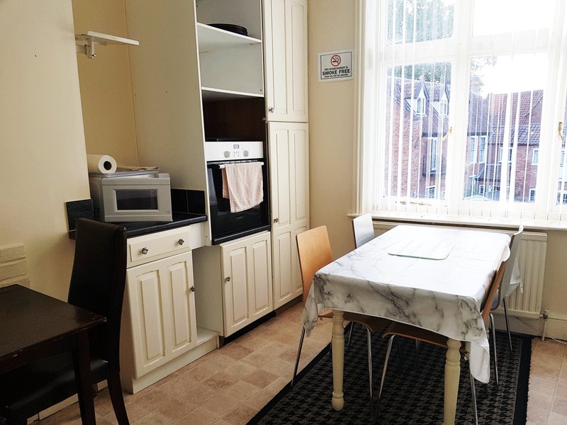 Kitchen-diner with cream cabinets, microwave, dining table and chairs, large window